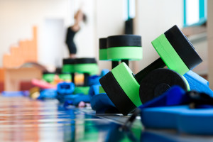 equipment for aqua aerobics on pool side. woman stretching on background